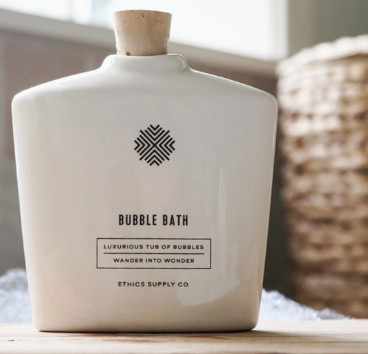White ceramic bottle labeled 'Bubble Bath' with a wooden cap on a neutral background